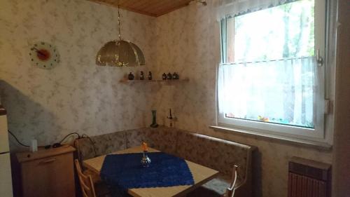 Zimmer mit einem Tisch und einem Fenster mit einem blauen Tischtuch. in der Unterkunft waldhaus lioba in Zichtau