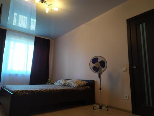 Schlafzimmer mit einem Bett, einem Ventilator und einem Fenster in der Unterkunft Comfortable apartments in Riwne