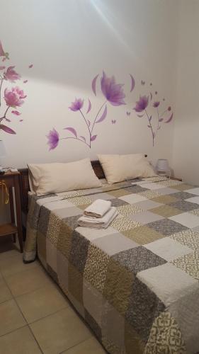 1 dormitorio con 1 cama con flores púrpuras en la pared en B&B Le Peonie, en Badesi