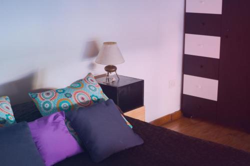 a bedroom with a bed with purple pillows and a lamp at Florida y Roja in Vicente López