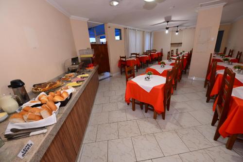 um restaurante com mesas e cadeiras com comida em exposição em Hotel Castanheira em Ipatinga