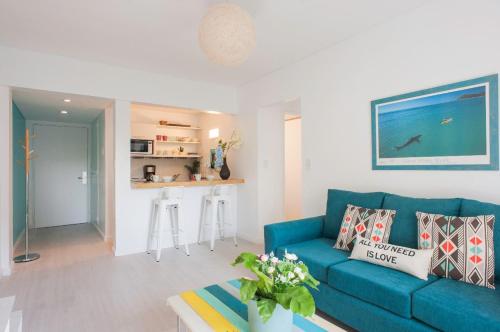 a living room with a blue couch and a kitchen at Soho Point Central in Buenos Aires