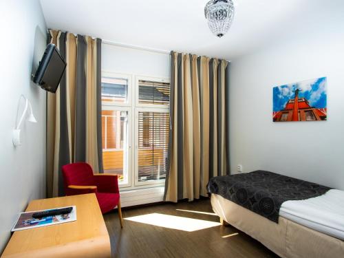 a bedroom with a bed and a desk and a window at Hotel Jahtihovi in Kuopio