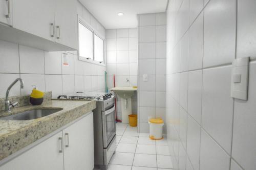 cocina de azulejos blancos con fregadero y fregadero en Apartamentos Verano, en Natal