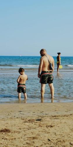 a group of people standing in the water at the beach at Hotel Villa Ada in Pozzallo
