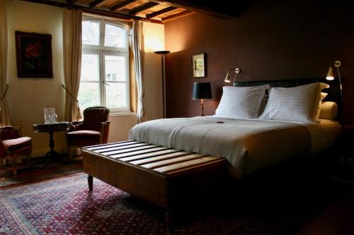 a hotel room with a bed, chair, lamp and window at B&B Au Lion D'or in Maastricht