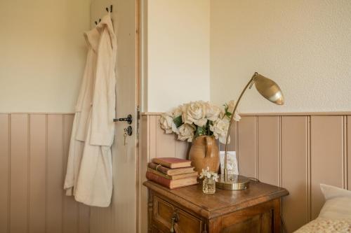 een slaapkamer met een tafel met een lamp en boeken bij boerderijkamer Zwanebloem in Onstwedde