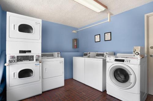 a laundry room with three washing machines and a washer and dryer at Kings Inn Anaheim at The Park & Convention Center in Anaheim