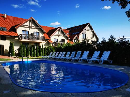 a swimming pool with chairs and a house at Hotel Santa Monica in Mikołajki