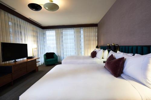 a hotel room with two beds and a flat screen tv at Fairlane Hotel Nashville in Nashville
