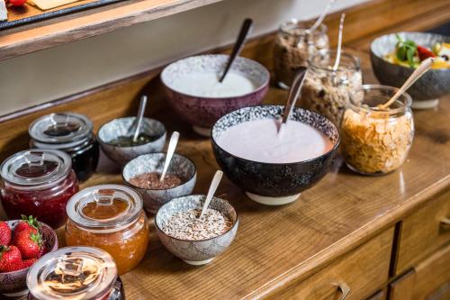 a wooden counter with bowls of yogurt and jars of food at B&B Villa Angelino in Ortisei