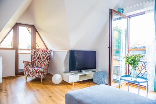 uma sala de estar com uma televisão e uma cadeira em Apartamenty Gubałówka em Zakopane