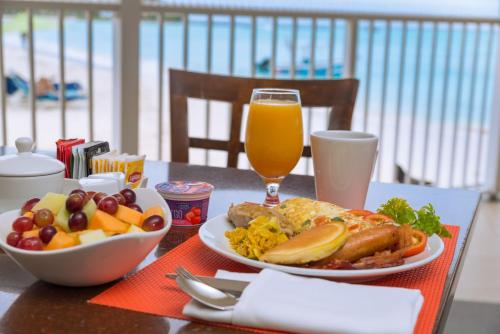 uma mesa com dois pratos de comida e um copo de suco de laranja em Radisson Aquatica Resort Barbados em Bridgetown