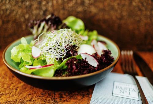 a bowl of salad on a table with a fork at Seevital Hotel & SPA - Ihr 4 Sterne Superior Hideaway direkt am See in Langenargen