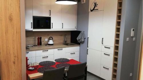 una pequeña cocina con una mesa roja y armarios blancos en Apartament Bielany Oczapowskiego en Varsovia