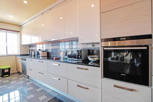 a kitchen with white cabinets and a large oven at Vila Lucia in Vila Praia de Âncora