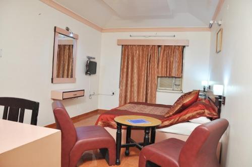 a room with a bed and a table and chairs at Hotel Savoy - Since 1951 in Jaipur