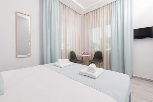 a white bedroom with a large bed and two chairs at Polyxeni's Studios in Limenas
