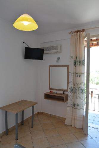 a room with a table and a tv and a window at Petros Giatras - Rooms in Zakynthos Town