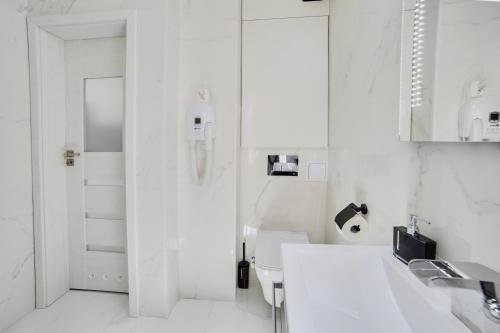 a white bathroom with a sink and a toilet at Apartament Lelewela 8 in Olsztyn