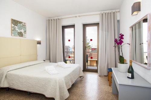 a white bedroom with a bed and a balcony at Hotel Villa Barbara in Can Picafort