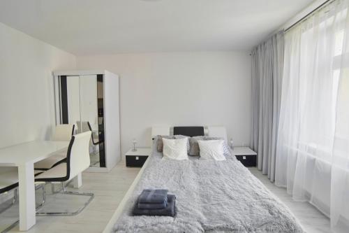 a white bedroom with a large bed and a desk at Apartament Lelewela 8 in Olsztyn