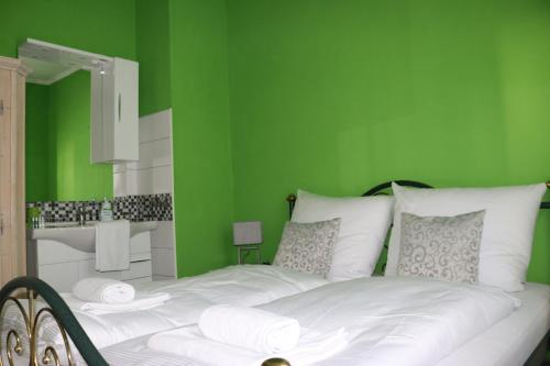 a green bedroom with a bed with white pillows at Hotel & Restaurant Pension Bei der Post in Bacharach