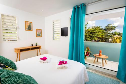 a bedroom with a bed and a large window at Villa Banc de sable, accès direct à la plage in Le Diamant