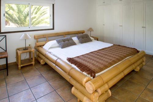 a large wooden bed in a room with a window at Finca Arbequina in Pájara