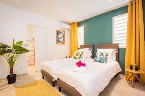 a bedroom with a large white bed with flowers on it at Villa Banc de sable, accès direct à la plage in Le Diamant