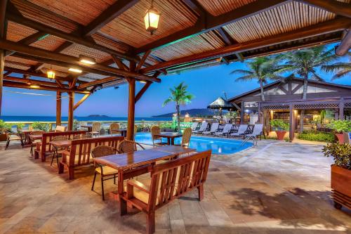 um pátio exterior com mesas e cadeiras e uma piscina em Costa Norte Ingleses Hotel em Florianópolis