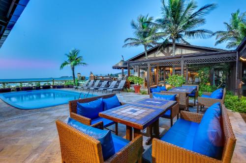 a patio with tables and chairs next to a swimming pool at Costa Norte Ingleses Hotel in Florianópolis