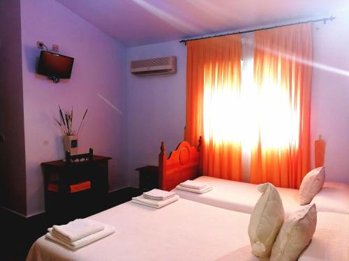 a bedroom with two beds and a window with towels at Hostal Restaurante Ego's in Campo de Criptana