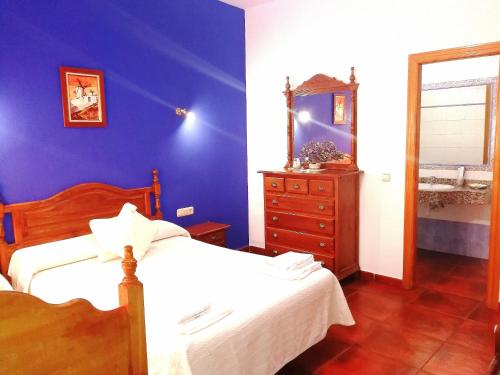 a blue bedroom with a bed and a dresser and a mirror at Hostal Restaurante Ego's in Campo de Criptana