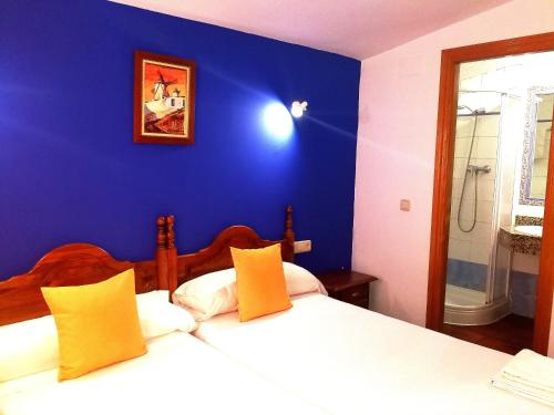 a bedroom with a blue wall and two beds at Hostal Restaurante Ego's in Campo de Criptana