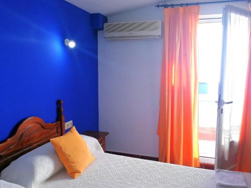 a blue bedroom with a bed and a window at Hostal Restaurante Ego's in Campo de Criptana