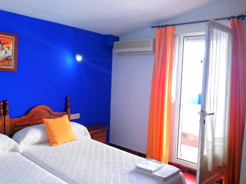 a blue bedroom with a bed and a window at Hostal Restaurante Ego's in Campo de Criptana
