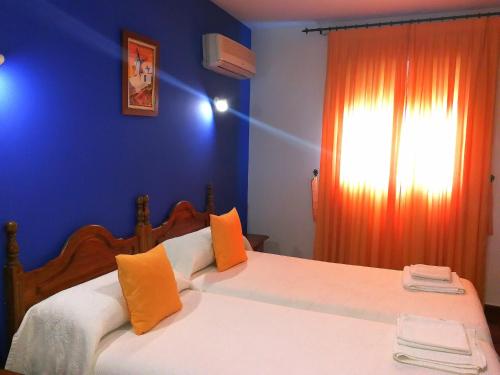 1 dormitorio con 1 cama grande con paredes azules y cortina naranja en Hostal Restaurante Ego's, en Campo de Criptana