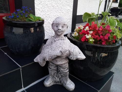 a statue of a child standing next to two potted plants at Ocean Heights B&B in Lissadell