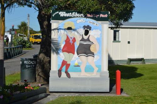 a sign with two girls on it on a street at Westshore Holiday Park in Napier
