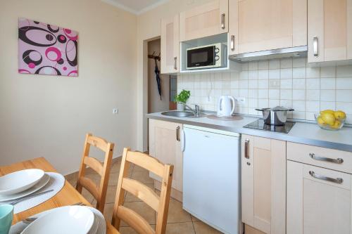 una cocina con armarios blancos y una mesa con sillas. en Sleepy3city Slaska 31, en Gdynia
