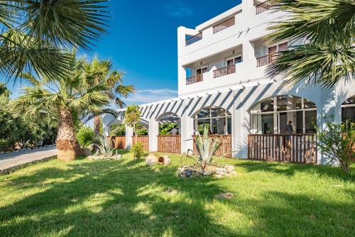 a white building with palm trees in front of it at Evripides Village in Kardamaina