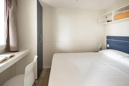 una camera con un letto bianco e una finestra di Camping Genova Est a Bogliasco