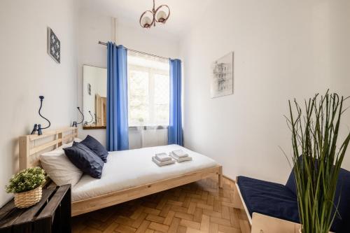 1 dormitorio con 1 cama con cortinas azules y ventana en WSTApartments CentralOne Górskiego 1, en Varsovia