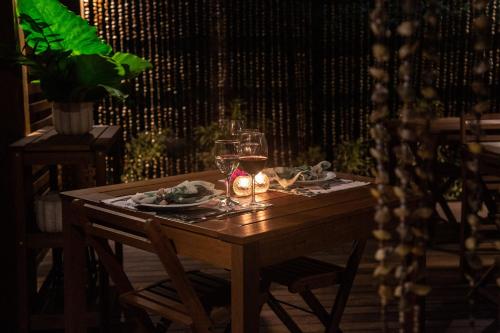 a wooden table with a glass of wine and candles at Dolphin Hotel in Fernando de Noronha