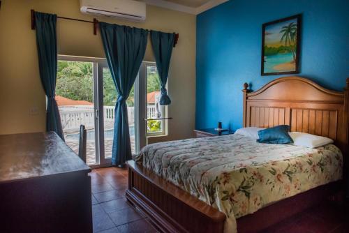 Un dormitorio con una cama con paredes azules y una ventana en West End Dive Resort, en West End