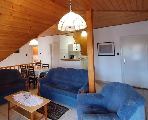 a living room with blue couches and a table at Kondor Vendégház in Badacsonytomaj
