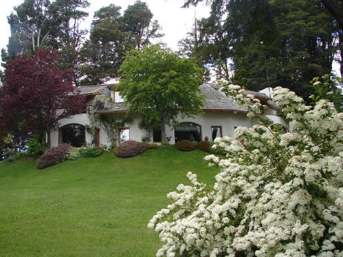 a house with white flowers in front of a yard at Bellevue in San Carlos de Bariloche