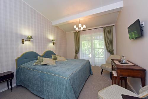 a hotel room with a blue bed and a television at Vila Klasika in Birštonas