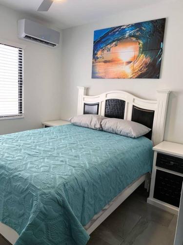 a bedroom with a large bed with a painting on the wall at Casita de Moana in Puerto Peñasco